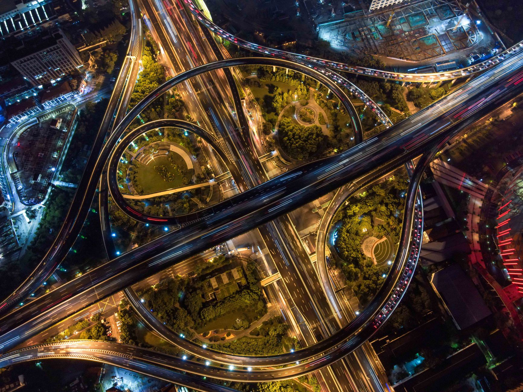 Aerial night view of a multi-lane expressway interchange, representative of the Ahmedabad-Dholera Expressway
